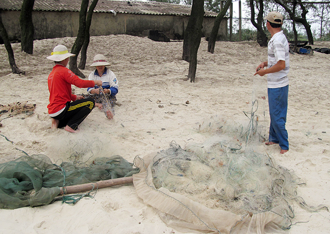 Thuyền lên bờ, ngư dân tranh thủ sửa lại ngư lưới cụ chờ lúc thời tiết thuận lợi.