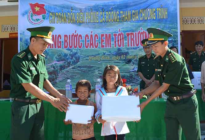 Cán bộ, chiến sĩ Đồn biên phòng Cà Roòng trao quà cho các em học sinh Ma Coong thuộc diện đỡ đầu.