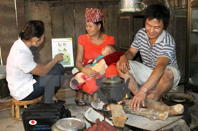 Nhân viên y tế thôn bản hướng dẫn bà mẹ chăm sóc sơ sinh tại xã Cà Tạ, huyện miền núi Kỳ Sơn, Nghệ An. (Ảnh: Dương Ngọc/TTXVN)