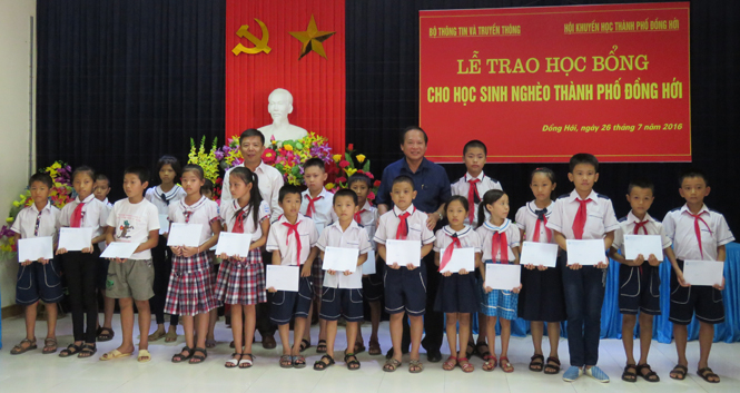 Đồng chí Trương Minh Tuấn, Ủy viên Trung ương Đảng, Phó trưởng Ban Tuyên giáo Trung ương, Bộ Trưởng Bộ Thông tin - Truyền thông và đồng chí Nguyễn Hữu Hoài, Phó bí thư Tỉnh ủy, Chủ tịch UBND tỉnh trao học bổng cho các em học sinh nghèo TP. Đồng Hới.