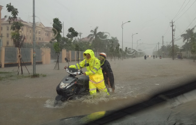 Chiến sĩ thuộc Đội CSGT Công an thành phố Đồng Hới hỗ trợ người dân qua vùng ngập sâu tại điểm giao cắt giữa đường Trần Quang Khải và Hữu Nghị.