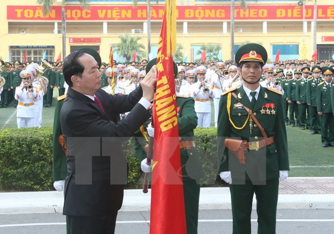 Chủ tịch nước Trần Đại Quang gắn Huân chương Độc lập hạng Nhì lên cờ truyền thống của Học viện. (Ảnh: Nhan Sáng/TTXVN)