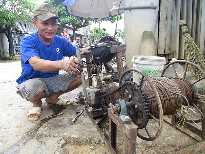 Anh Lê Văn Đàn bên chiếc máy tời lúa vừa hoàn thành.