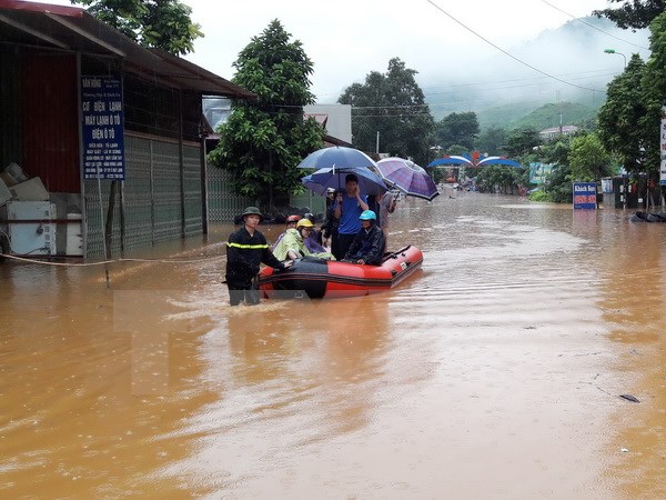 Lực lượng chức năng dùng xuồng đưa người dân vượt qua đoạn ngập sâu tại thị trấn Ít Ong, huyện Mường La. (Ảnh: Nguyễn Cường/TTXVN)