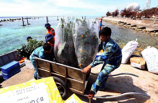 Các cán bộ, chiến sĩ đảo Phan Vinh A tiếp nhận hàng quà Tết, nhu yếu phẩm từ tàu Quân y 561. (Ảnh: Quang Quyết/TTXVN)