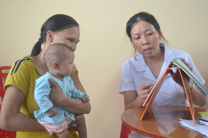 Cán bộ y tế đang hướng dẫn cho người dân cách chăm sóc sức khỏe và phòng chống suy dinh dưỡng cho trẻ nhỏ
