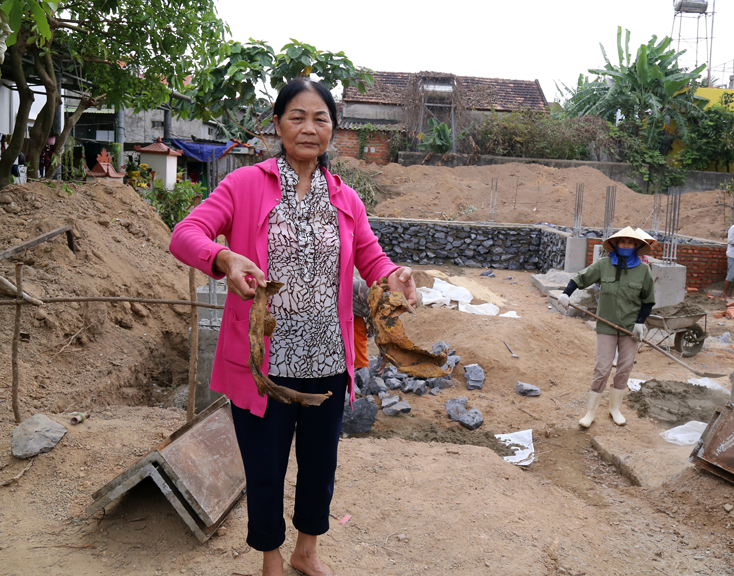 Bà Võ Thị Mai cầm hai vành sắt, phần còn lại của quả bom được các chuyên gia MAG tháo gỡ tại nhà mình.