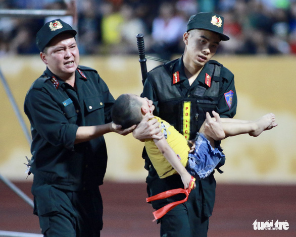 Cháu bé bị ngất xỉu được hai cảnh sát cơ động đưa xuống sân để cấp cứu - Ảnh: ANH NGUYỄN