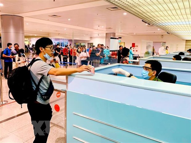 Cán bộ công an cửa khẩu Tân Sơn Nhất chủ động trang bị đầy đủ khẩu trang, găng tay trong khi làm nhiệm vụ. (Ảnh: Thành Chung/TTXVN)