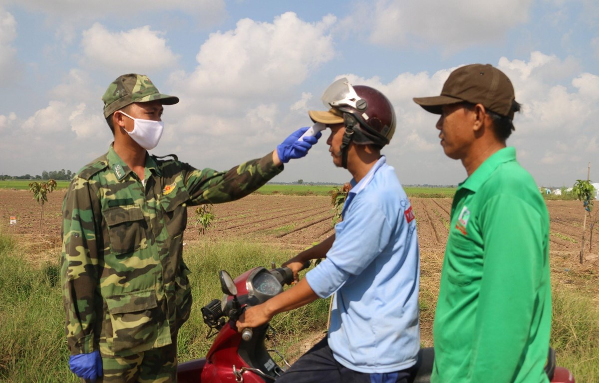 Cán bộ chiến sỹ Đồn Biên phòng quốc tế Vĩnh Xương - Bộ đội Biên phòng tỉnh An Giang tuyên truyền và phát khẩu trang vải người dân khu vực biên giới. (Ảnh: Công Mạo./TTXVN)