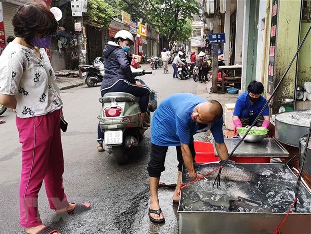 Vẫn còn những người bán hàng không thực hiện đeo khẩu trang khi tiếp xúc với người mua. (Ảnh: Thanh Tùng/TTXVN)