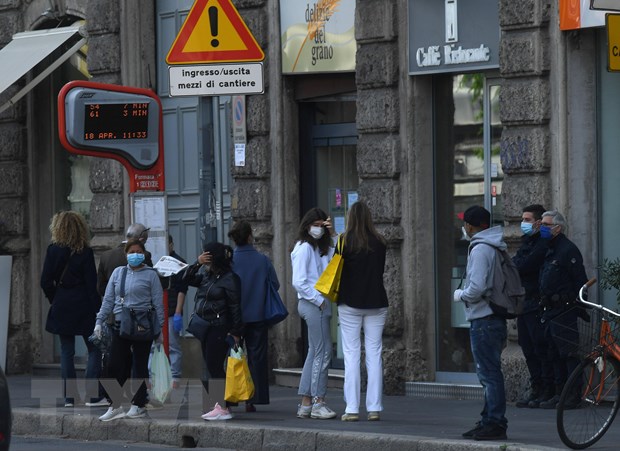  Người dân đợi xe buýt tại bến xe ở Milan, Italy ngày 18-4-2020 trong bối cảnh dịch COVID-19 đang hoành hành. (Ảnh: THX/TTXVN)
