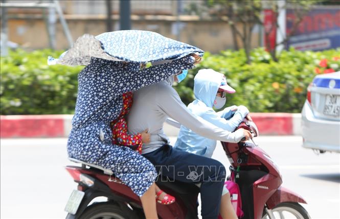  Người dân tìm mọi cách tránh nắng khi tham gia giao thông. Ảnh minh họa: Thành Đạt/TTXVN
