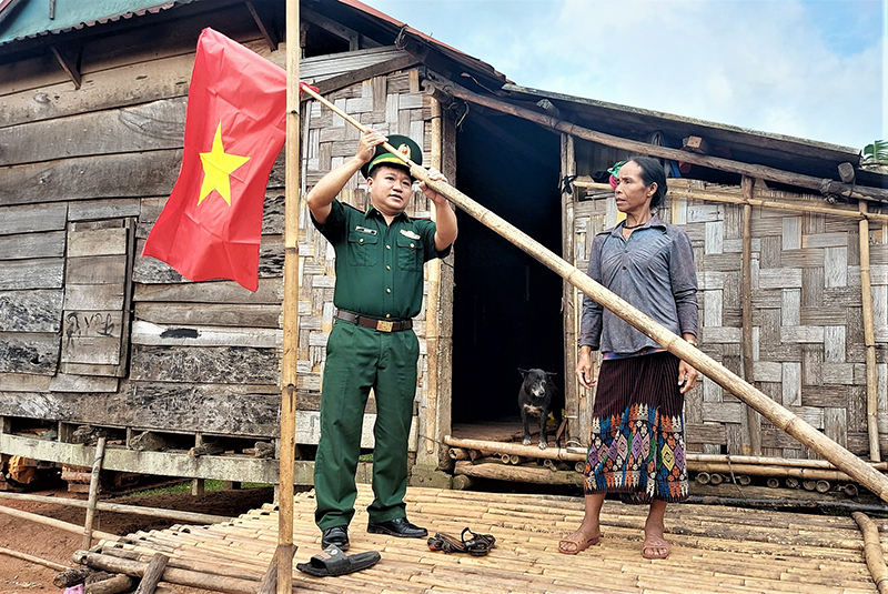 Cán bộ Đồn Biên phòng Cà Roòng hướng dẫn người dân bản 61, xã Thượng Trạch (Bố Trạch) treo cờ Tổ quốc.