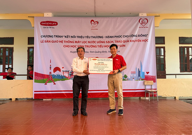 Ông Trần Đình Quân, Chủ tịch HĐTV Dai-ichi Life VN, Chủ tịch Quỹ Vì cuộc sống tươi đẹp (phải), trao biểu trưng số tiền tài trợ cho thầy Nguyễn Xuân Quy, Hiệu trưởng trường Tiểu học Thiết Sơn 