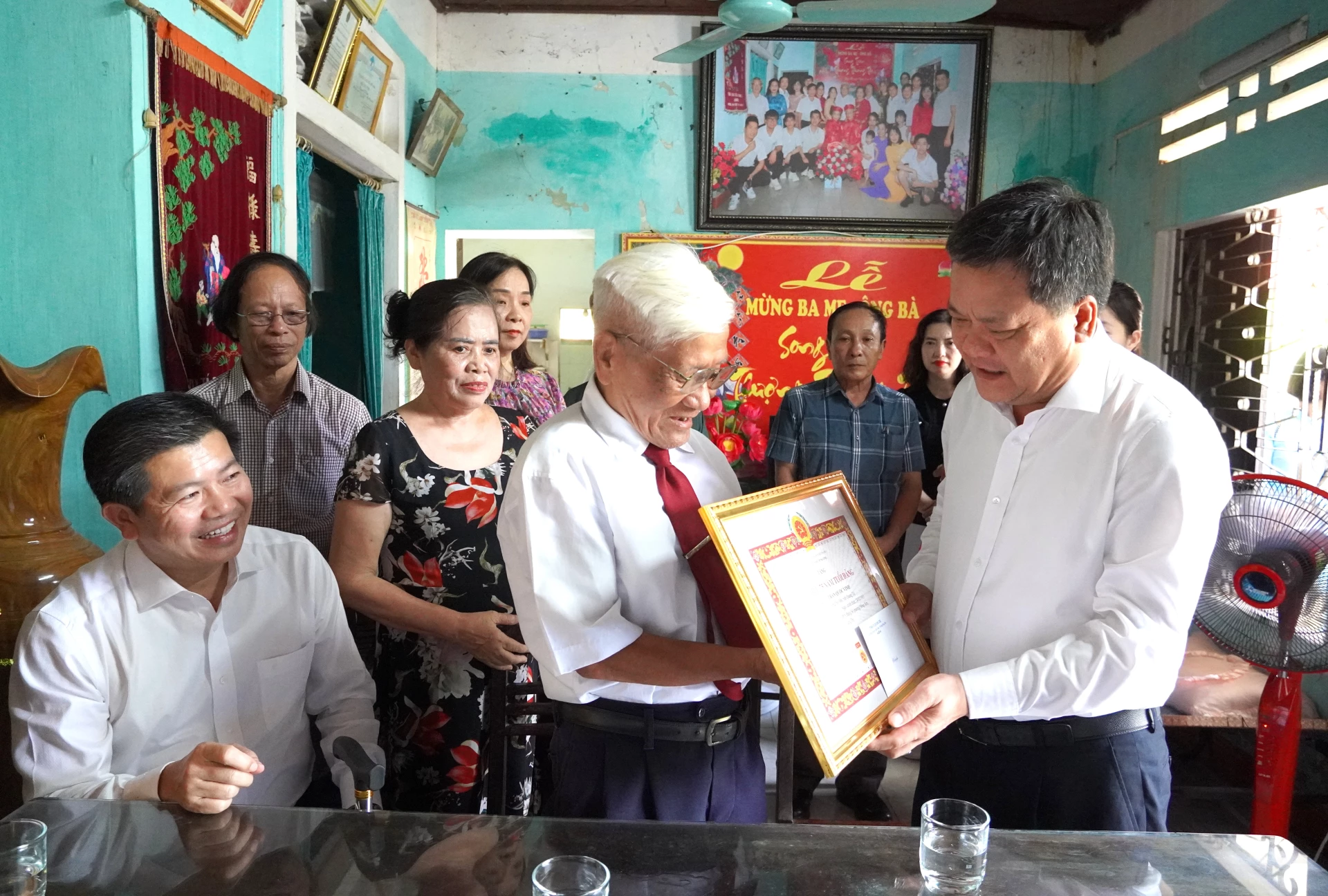 Phó Bí thư Tỉnh ủy, Chủ tịch UBND tỉnh Trần Phong trao huy hiệu 75 năm tuổi Đảng cho  đảng viên Trần Quốc Vinh - Ảnh: Trung Đức