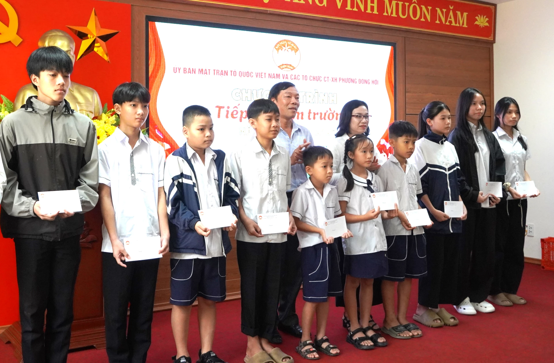 Đại diện Ủy ban MTTQVN phường Đồng Hới trao quà cho các học sinh. Ảnh: H.Tr