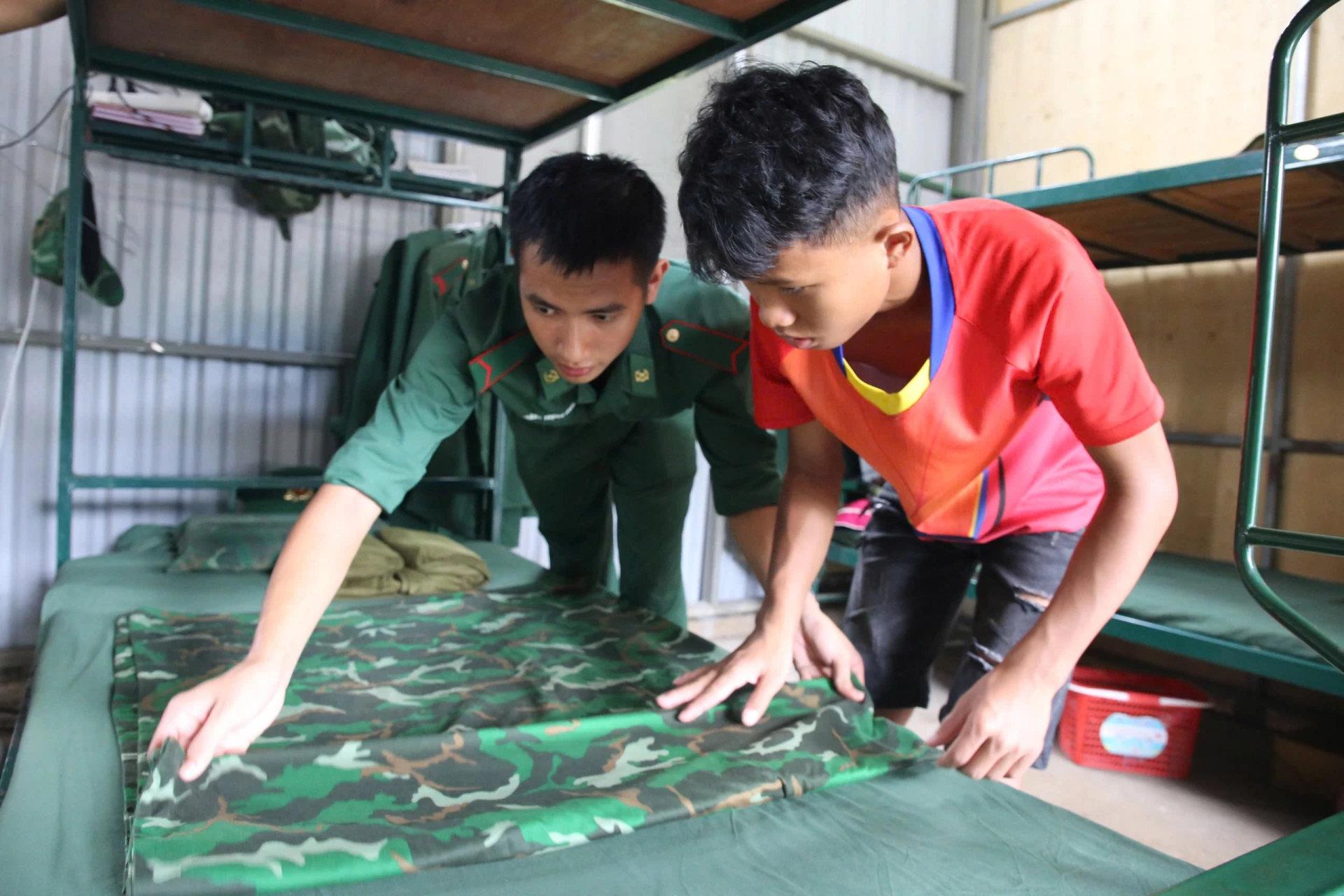 Hồ Lanh được Bộ đội Biên phòng hướng dẫn cách xếp chăn màn trước ngày đi nhập học ở xa - Ảnh: P.P