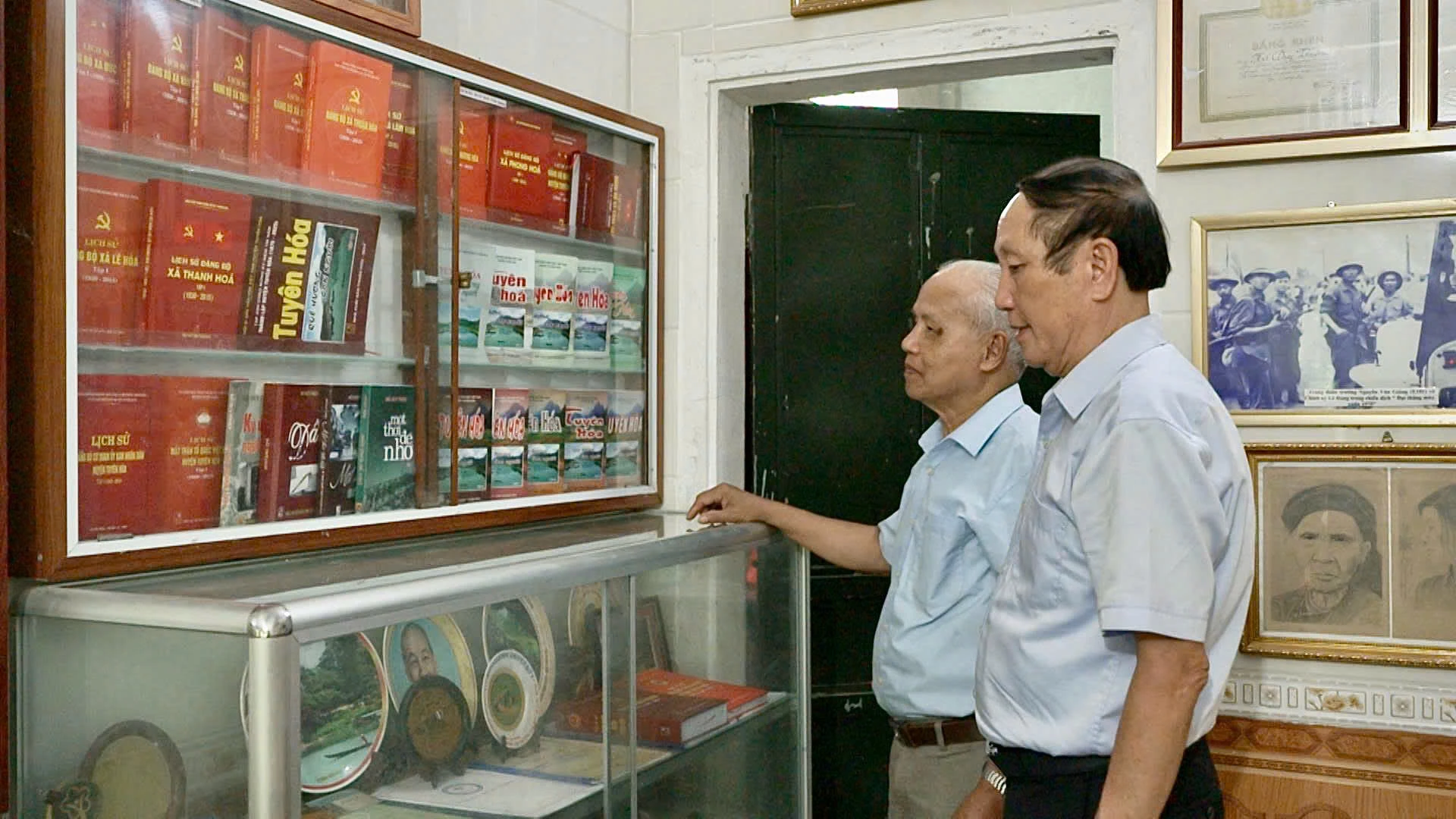 Ông Hồ Duy Thiện (bên trái) giới thiệu tủ sách “Tuyên Hóa, quê hương, con người” và các tập lịch sử địa phương do ông biên soạn - Ảnh: M.H